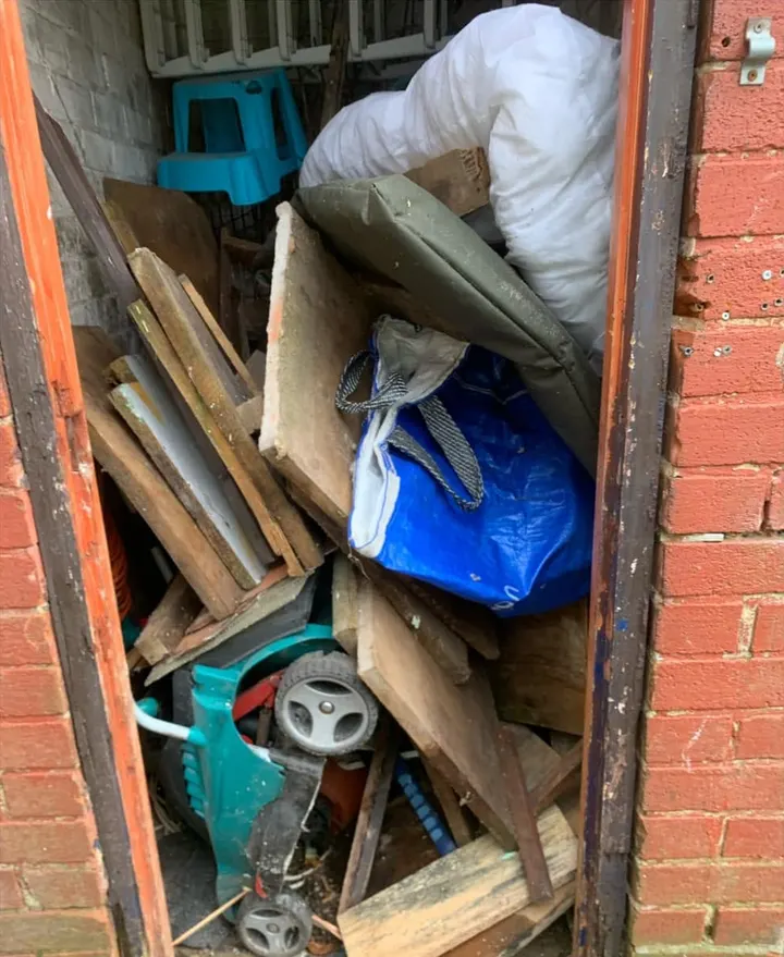 Before: a brick outhouse jammed with timber, bags and an old lawnmower