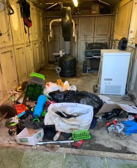 Before: bags, toys, crates and clutter covering a garage floor in front of gym equipment
