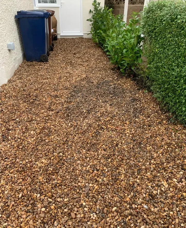 After: a clear gravel side path between a house and a hedge