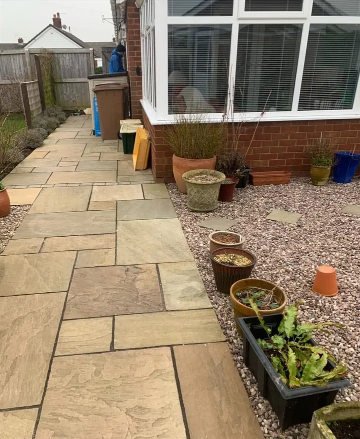 After: a clear stone patio path beside a conservatory