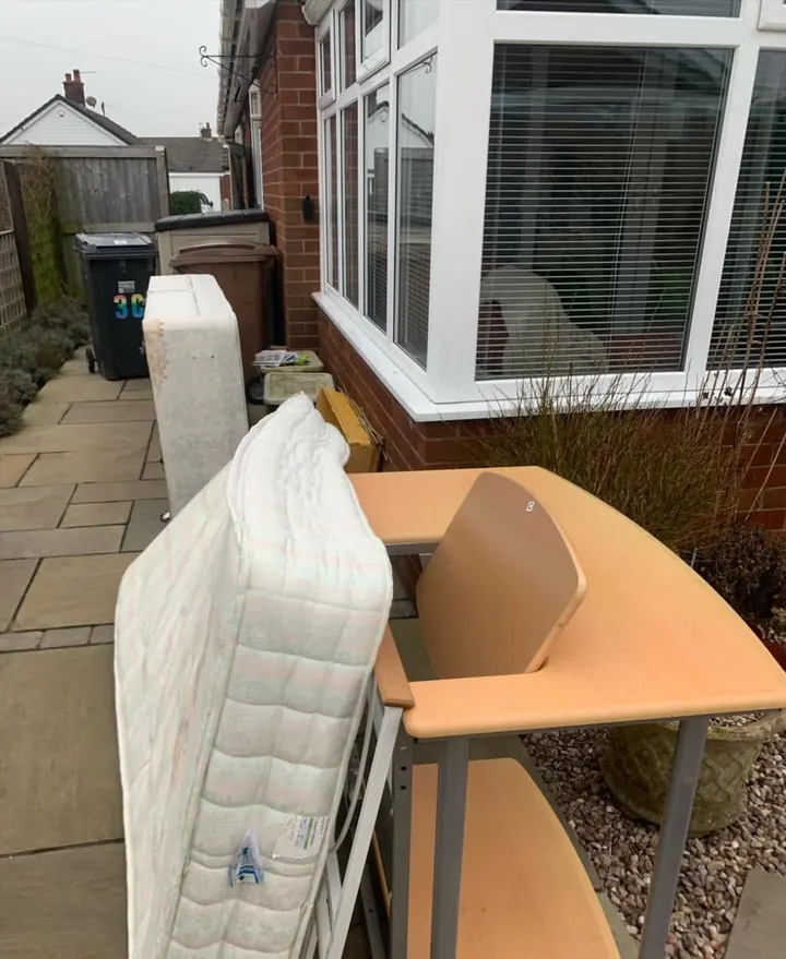 Before: a mattress, bed base and corner desk on a patio