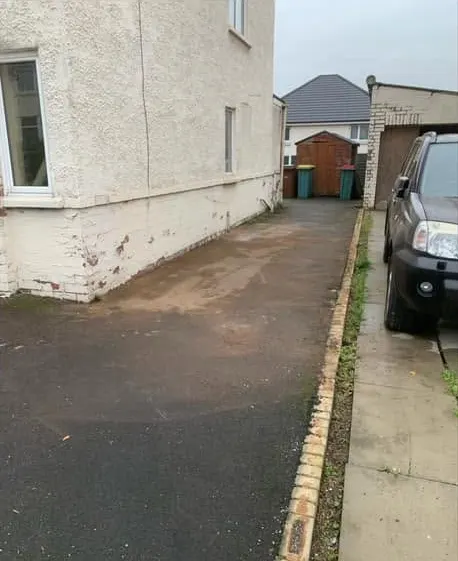 After: a clear tarmac drive along the side of a rendered house
