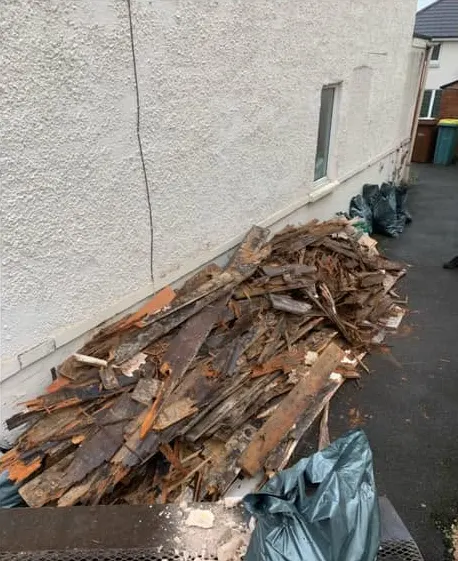 Before: a heap of rotten timber and bagged rubble against a rendered wall